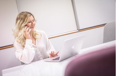 Digimarkkinointi -asiantuntija puhuu puhelimeen tietokoneen ääressä.